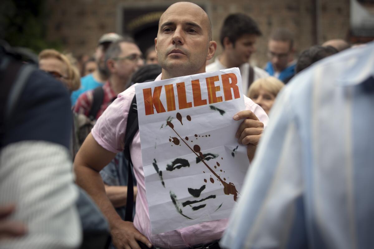 A protester holds a poster depicting Russia's President Putin along with sign "Killer" during a protest rally in downtown Sofia in front of Bulgarian Presidency building on Wednesday, Aug 10, 2022. Hundreds of Bulgarians gathered to express their fear that after the pro-Western government was toppled in June allegedly because of Sofia's hard stance against Kremlin's invasion in Ukraine and its refusal to pay Gazprom in rubles, the current caretaker government could now redraw some foreign policy lines. (AP Photo/Valentina Petrova)