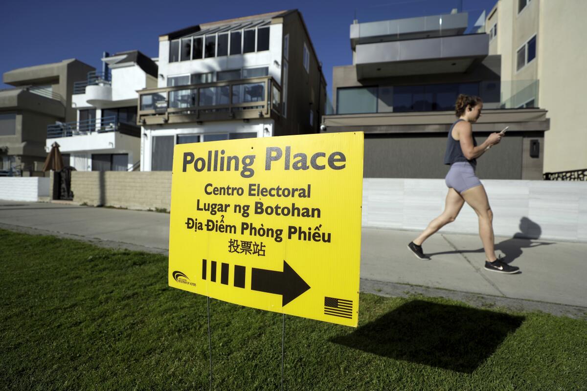 In this March 3, 2020 photo a woman runs by a polling place during primary elections in San Diego. 