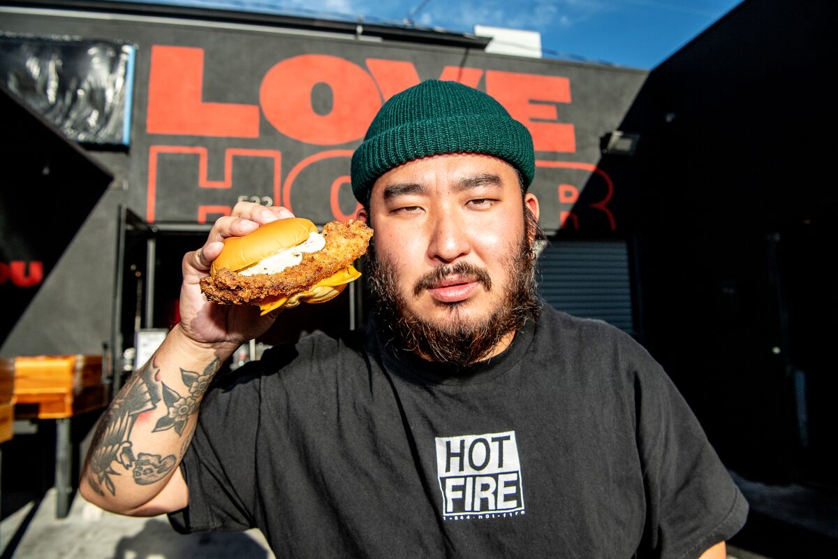 Portrait of owner Mike Pak showcasing the fish sandwich outside his restaurant, Love Hour, in Ktown.