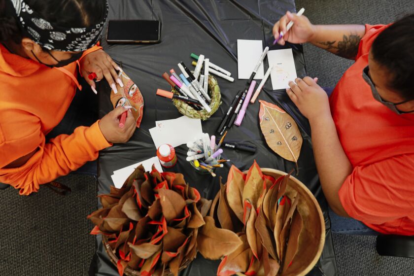Left, Joy Becenti and Lianela Tudela decorate magnolia leaves to attach to a paper tree at the Indigenous Resource Center at SDSU on Thursday, September 30, 2021. Staff and students at San Diego State University's Native American Resource Center will be participating in Orange Shirt Day, a day of remembrance in honor of Indigenous children who forcibly attended and/or died at residential boarding schools.(Photo by Sandy Huffaker for The San Diego Union-Tribune)