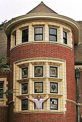 John Gochá hangs out of an open stained-glass window at his 1904 mansion in the Country Club Park area of Los Angeles. He and his co-owner slashed their annual property tax bill from $20,000 to $10,000 by taking advantage of a 1972 state law that provides a tax break for owners of historic-landmark homes who agree to use the savings to keep them in tip-top shape.