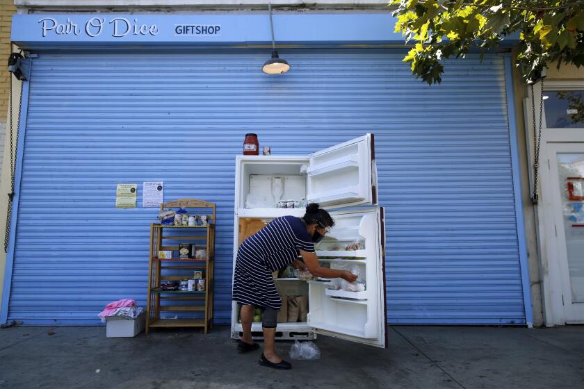 LOS ANGELES, CA - JULY 28: Rosalinda Martinez restocks a fridge and pantry shelving offering free food for the community on Figueroa Street in Highland Park on Tuesday, July 28, 2020 in Los Angeles, CA. Martinez comes twice a day to clean and restock the food. (Dania Maxwell / Los Angeles Times)