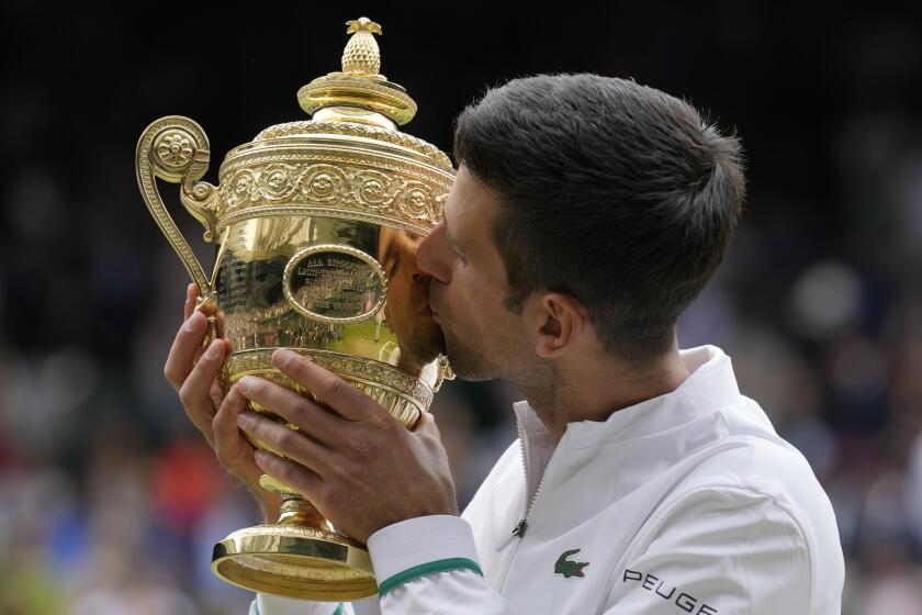 Serbia's Novak Djokovic kisses the winners trophy as he poses for photographers after he defeated Italy's Matteo Berrettini in the men's singles final on day thirteen of the Wimbledon Tennis Championships in London, Sunday, July 11, 2021. (AP Photo/Kirsty Wigglesworth)