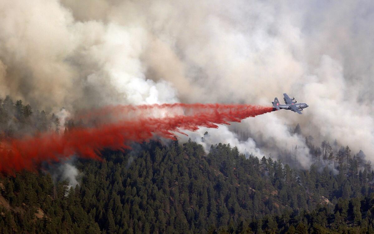 A military C-130 drops a load of fire retardant on a wildfire on the northern edge of Pike National Forest.