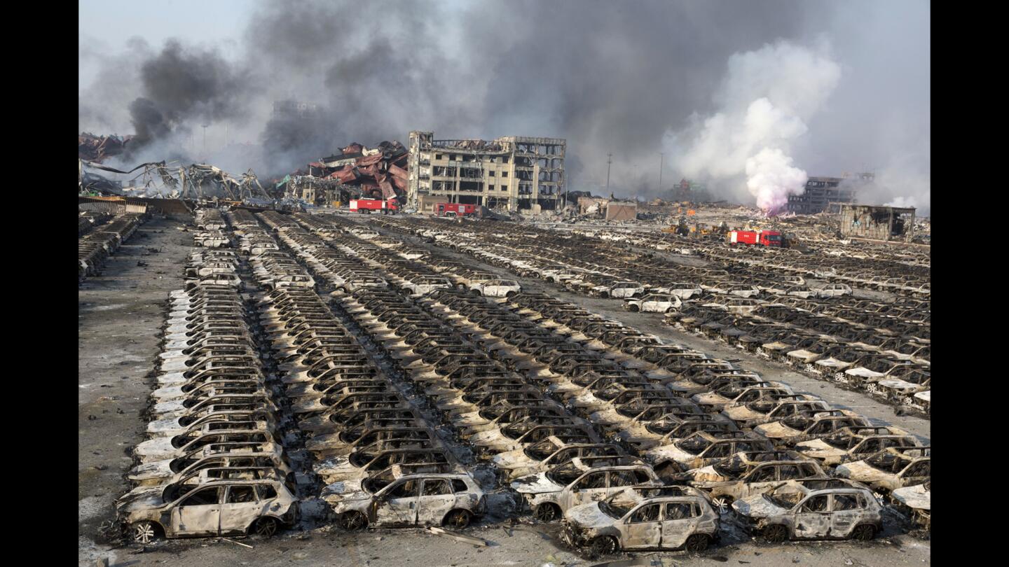 Smoke billows on Aug. 13 from the site of a pair of explosions that reduced a parking lot filled with new cars to charred remains in Tianjin, China.