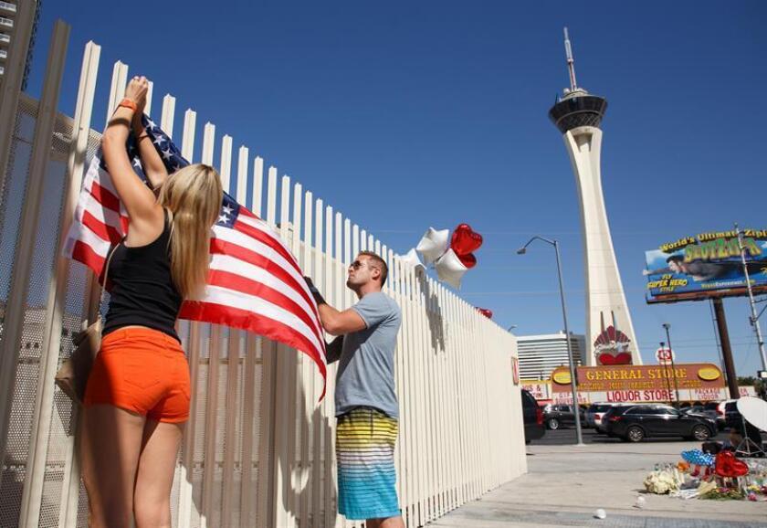 Personas ponen una bandera de Estados Unidos cerca de la Torre Stratosphere como parte de un monumento improvisado a las víctimas del tiroteo masivo en Las Vegas, Nevada (EE.UU.). EFE/Archivo