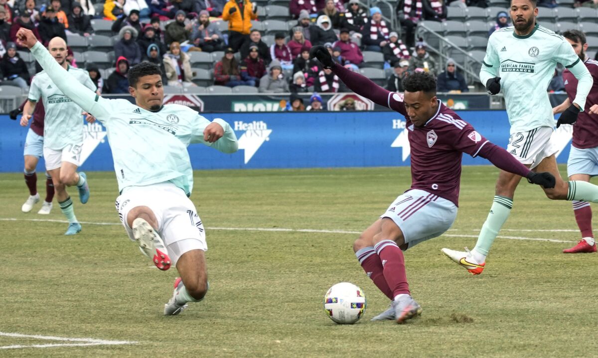 Colorado Rapids' Jonathan Lewis, right, kicks the ball as Atlanta United's Miles Robinson defends during the first half of an MLS soccer match Saturday, March 5, 2022, in Commerce City, Colo. (AP Photo/David Zalubowski)