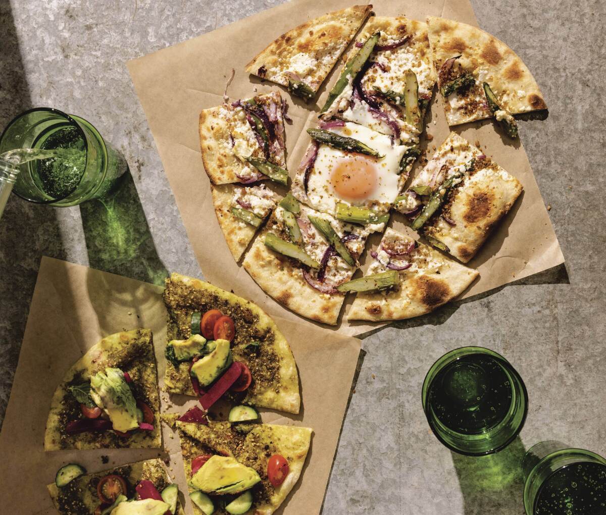 An overhead view of flatbread that's been sliced in pieces, with toppings including egg and avocado.