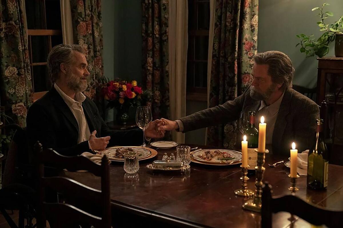 Two graying men hold hands at the dinner table in a scene from "The Last of Us."