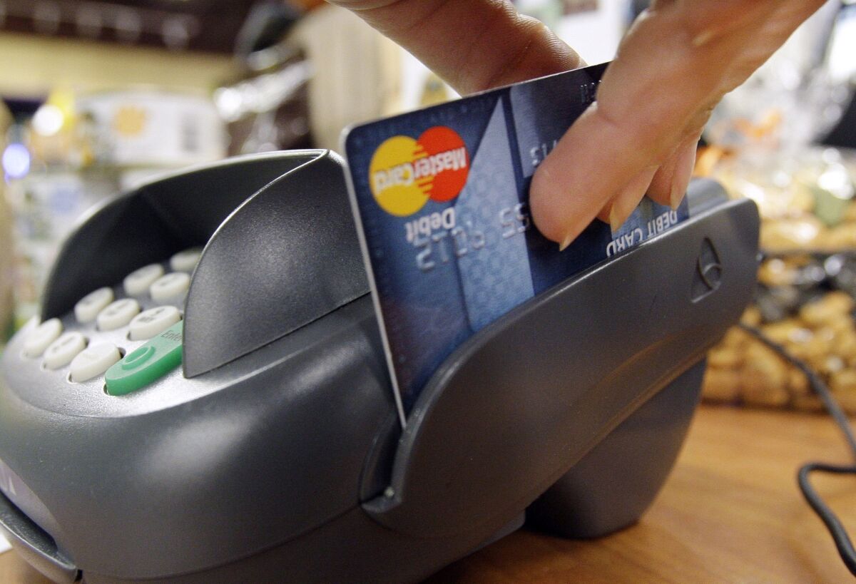 A customer swipes a MasterCard debit card through a machine at a shop in Seattle. Household debt jumped $241 billion to $11.5 trillion in the fourth quarter, the biggest increase since the third quarter of 2007.