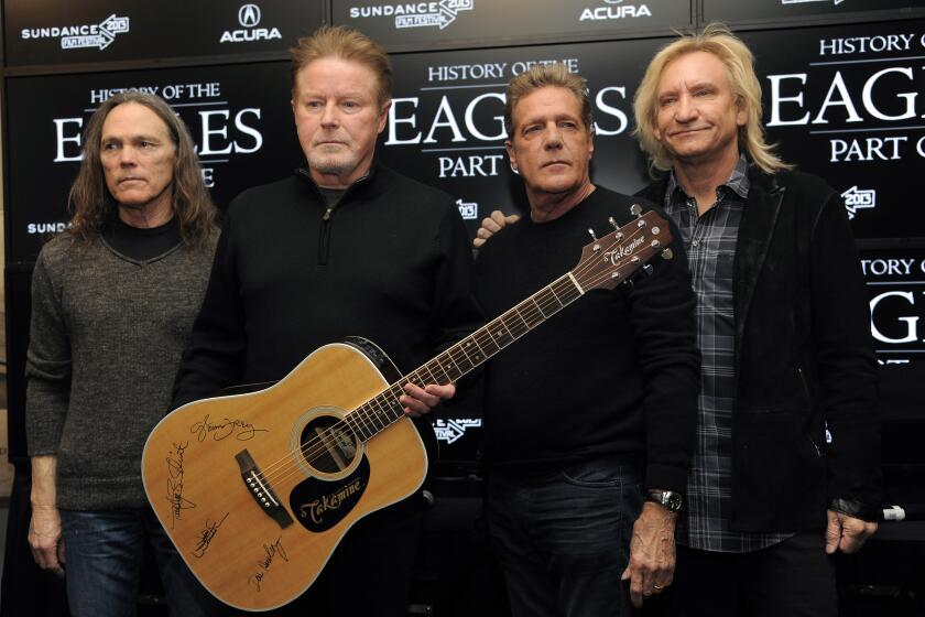 ARCHIVO - Los miembros de los Eagles Timothy B. Schmit, Don Henley, Glenn Frey y Joe Walsh, de izquierda a derecha, posan con una guitarra autografiada después de una conferencia de prensa en el Festival de Cine de Sundance, el 19 de enero de 2013 en Park City, Utah. (Foto por Chris Pizzello/Invision/AP, archivo)