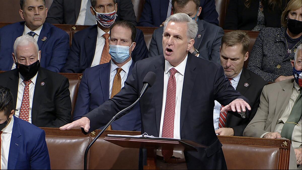 Kevin McCarthy speaks at a lectern with fellow Republicans seated behind him 