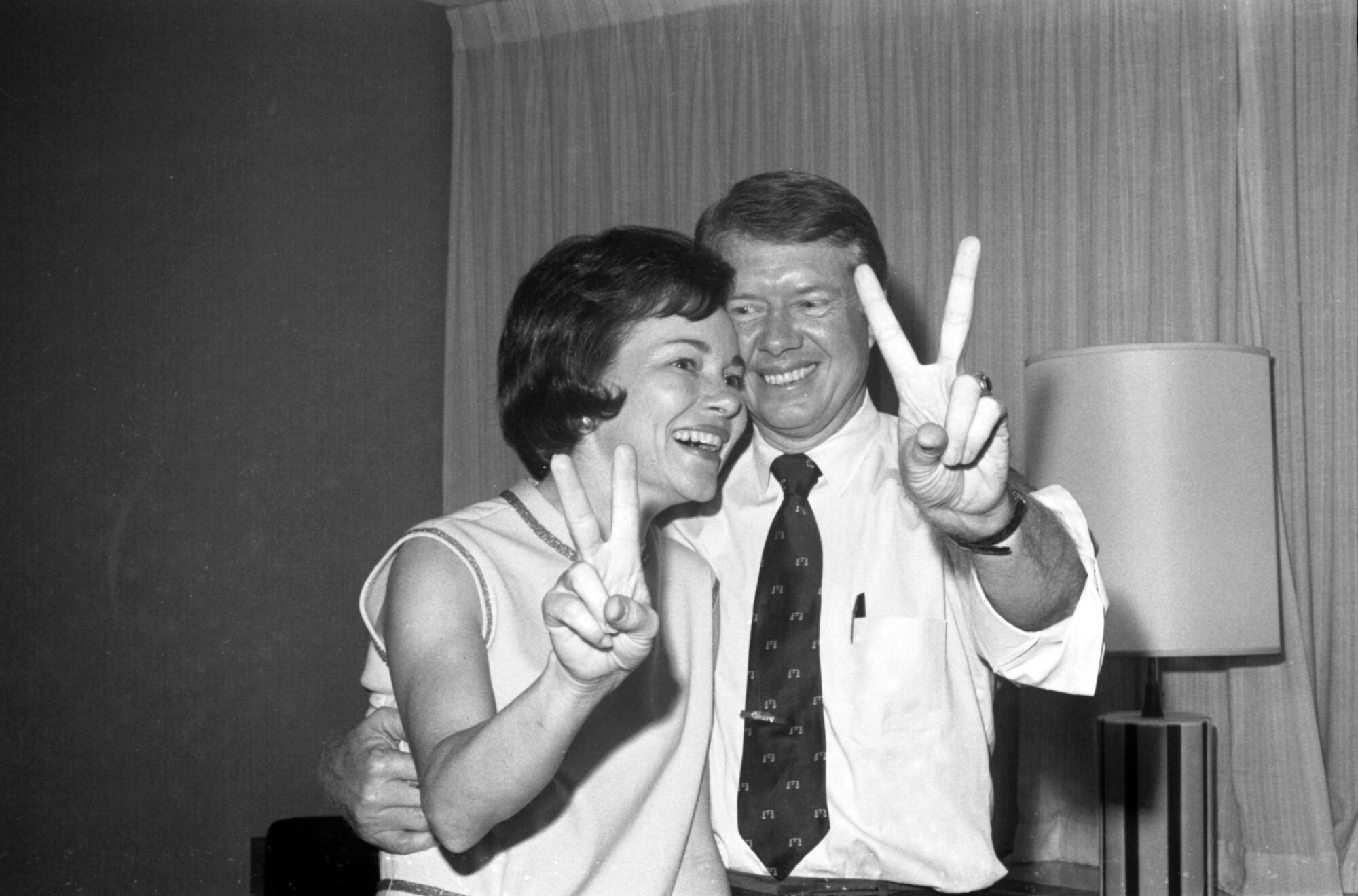 Jimmy and Rosalynn Carter hold up their fingers in the V for victory sign
