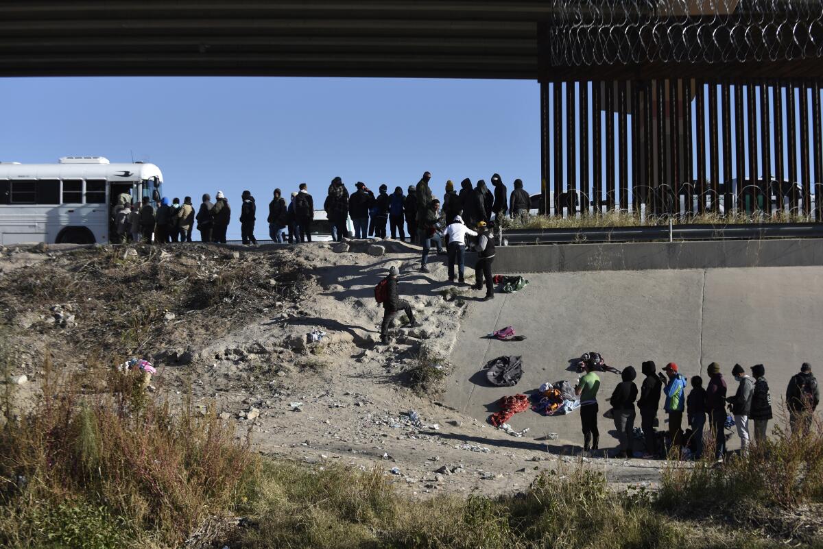 Decenas de migrantes esperan a subir a un autobús del gobierno estadounidense tras cruzar la frontera desde Ciudad Juárez