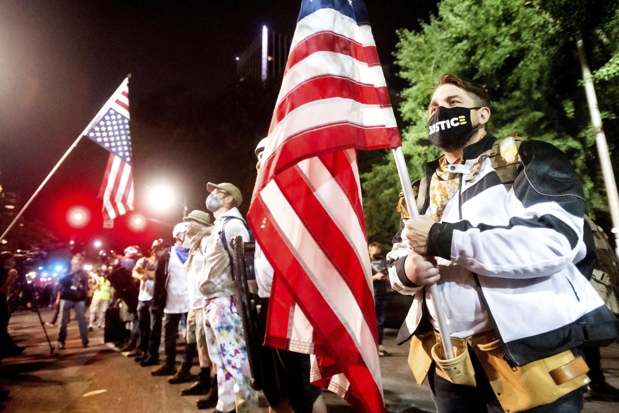 Navy veteran Adam Winther holds a flag while forming a "Wall of Vets" during a Black Lives Matter protest in Portland.