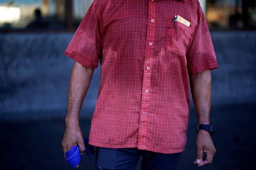 FILE - A man's shirt is bathed in sweat before seven in the morning as he parks cars and provides security for a downtown cafe July 20, 2023, in Mexicali, Mexico. (AP Photo/Gregory Bull, File)