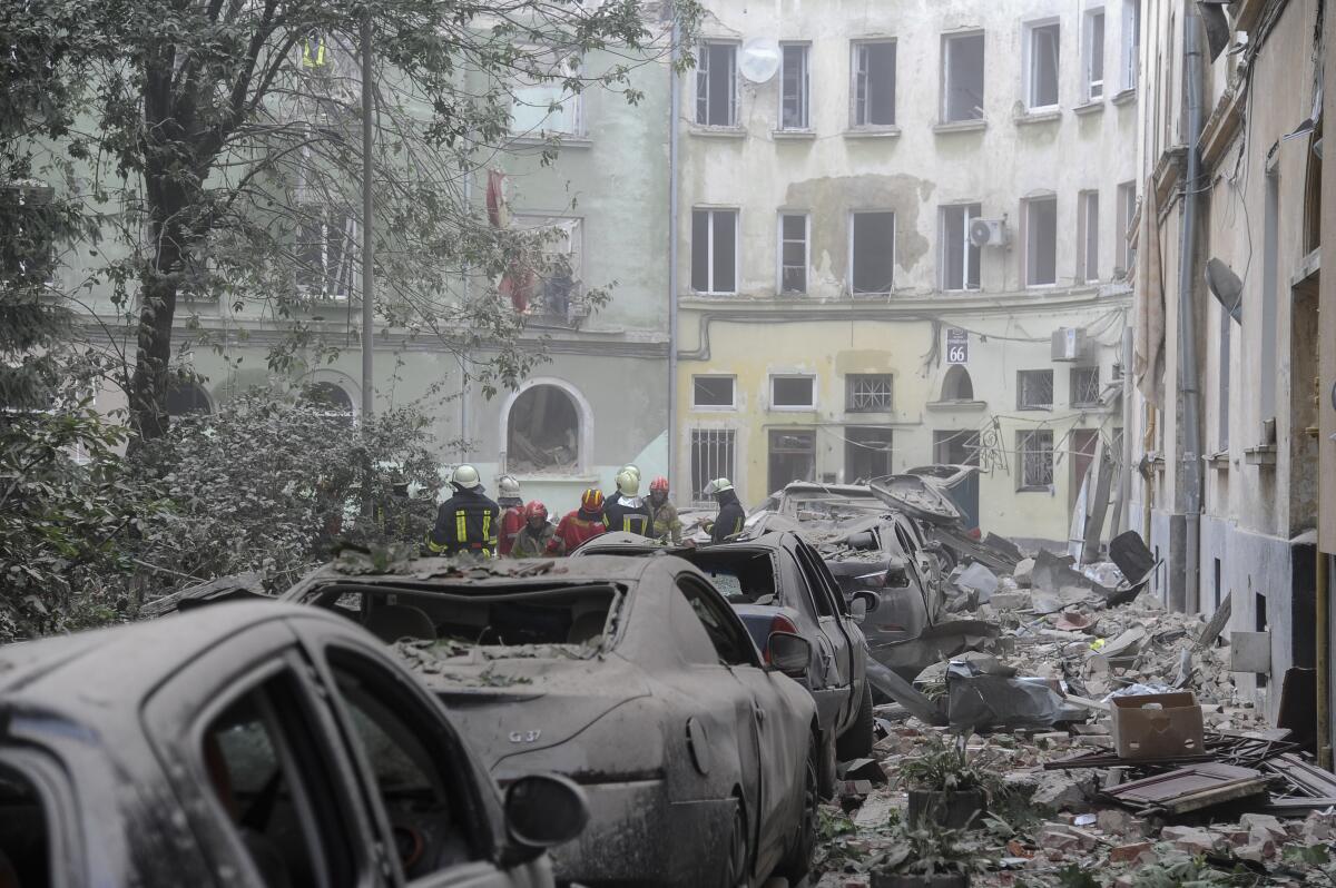 Emergency workers gather in a street amid charred cars and rubble