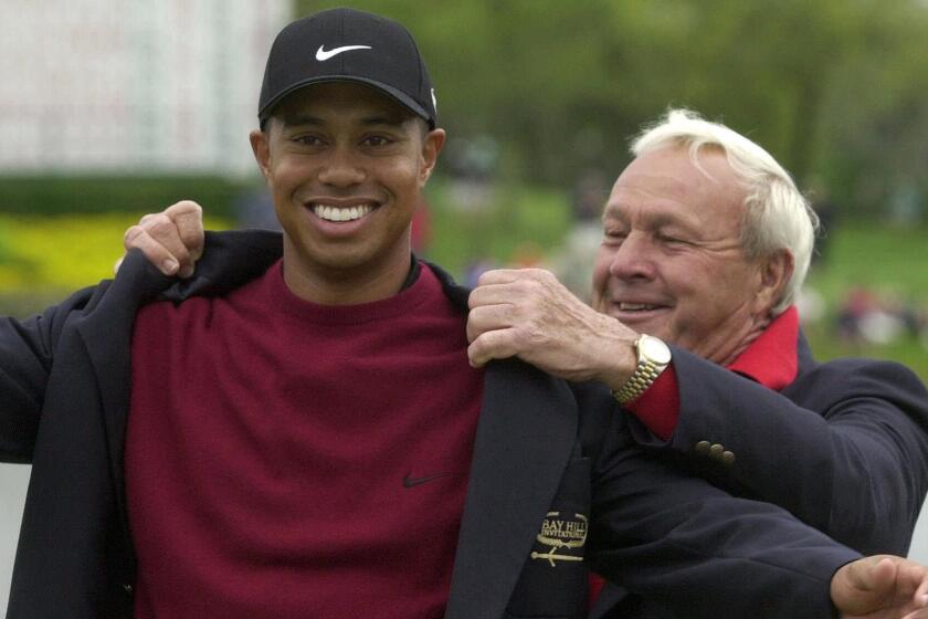 Tiger Woods is helped into his winner's jacket by golfing great Arnold Palmer after taking a victory at the 2001 Bay Hill Invitational in Orlando, Fla.