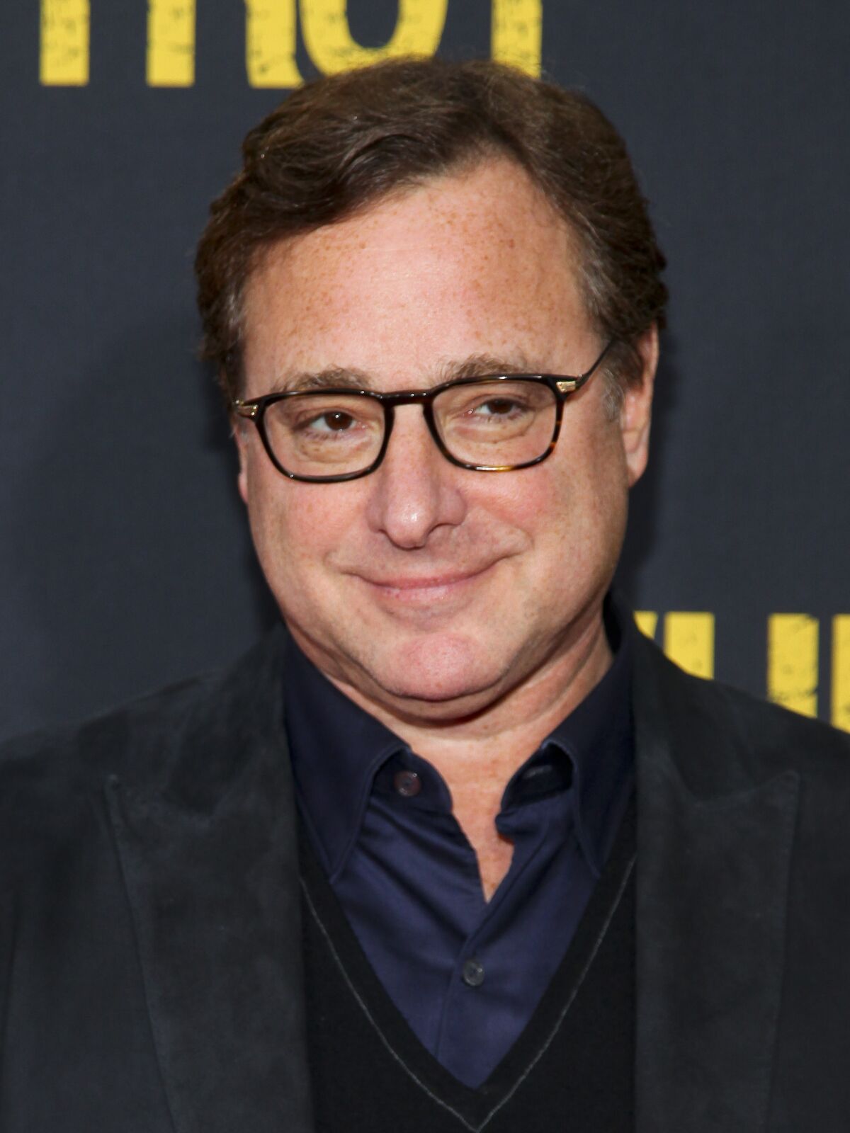 A man in eyeglasses wearing a dark suit.