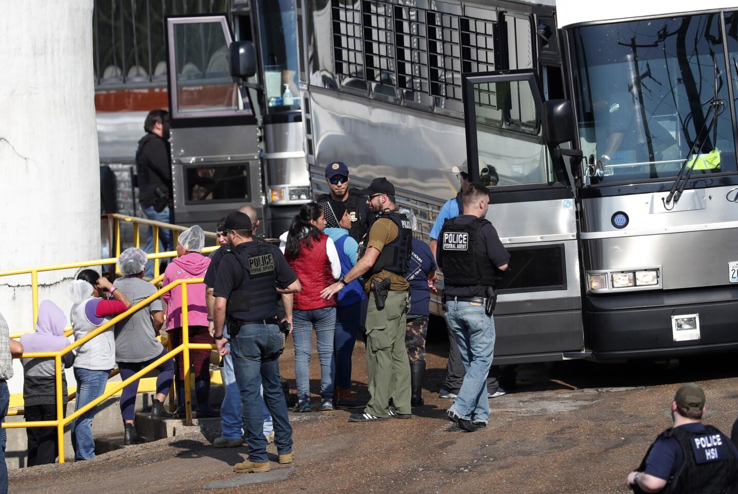 Handcuffed female workers are escorted into a bus for transportation to a processing center following a raid by U.S. immigration officials at a Koch Foods Inc. plant in Morton, Miss., on Wednesday.