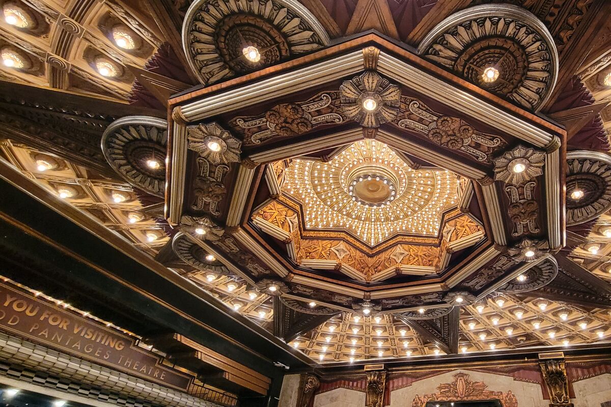 The ceiling of a theater's entry canopy is decorated with a recessed starburst illuminated with many small lightbulbs.