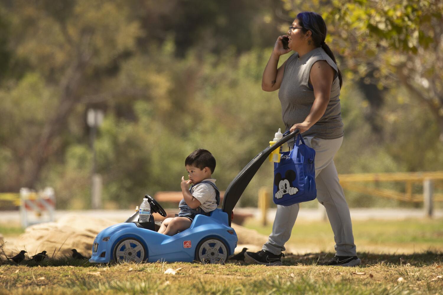 ENCINO, CA - August 18: Lake Balboa Anthony C. Beilenson Park on Monday, Aug. 18, 2025 in ENCINO, CA. Little hot for a convertible as Adrian Garcia walks her 2-year-old son Benjamin Hernandez at Lake Balboa Anthony C. Beilenson Park as a heat wave is expected to bake Southern California and much of the American Southwest this week, with triple-digit highs and elevated fire conditions set to begin Wednesday and last for several days. (Al Seib / For the Los Angeles Times)