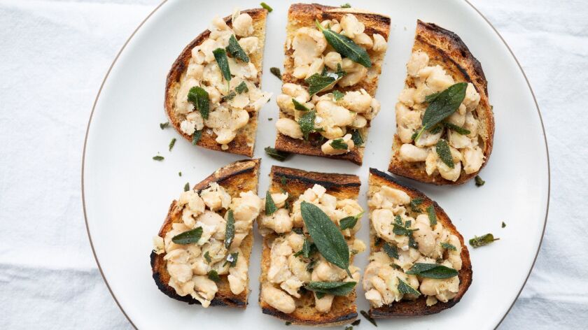 Canned white beans are warmed in herb oil then smashed on toast for an easy pantry meal.