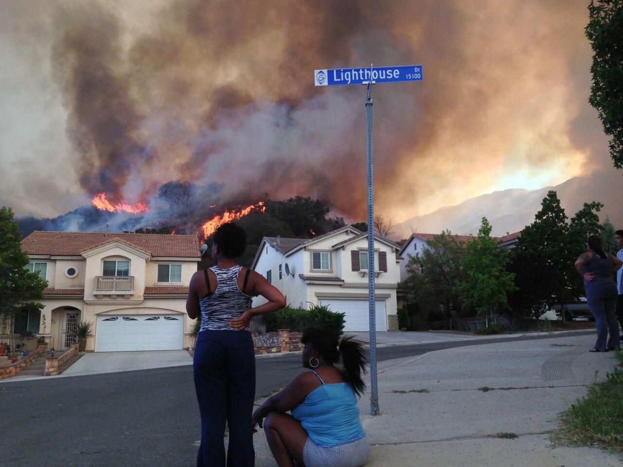 Residents Katera Hutchins, left, and mother Janna Lucas watch as flames approach their Lake Elsinore-area neighborhood as the fire grew.