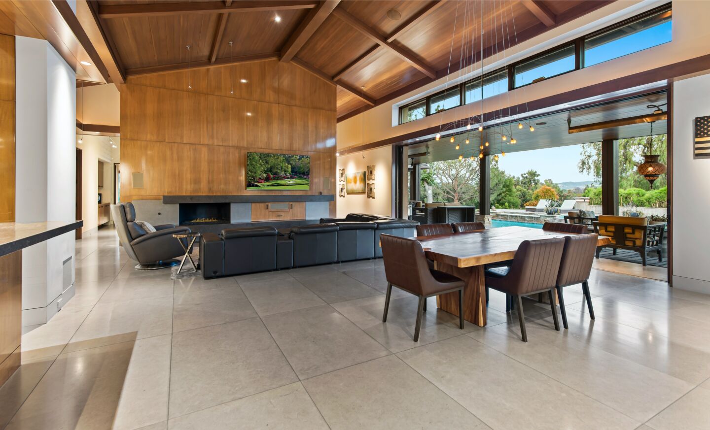 The open floor plan gas high wooden ceiling and living and dining furniture with nearby windows.