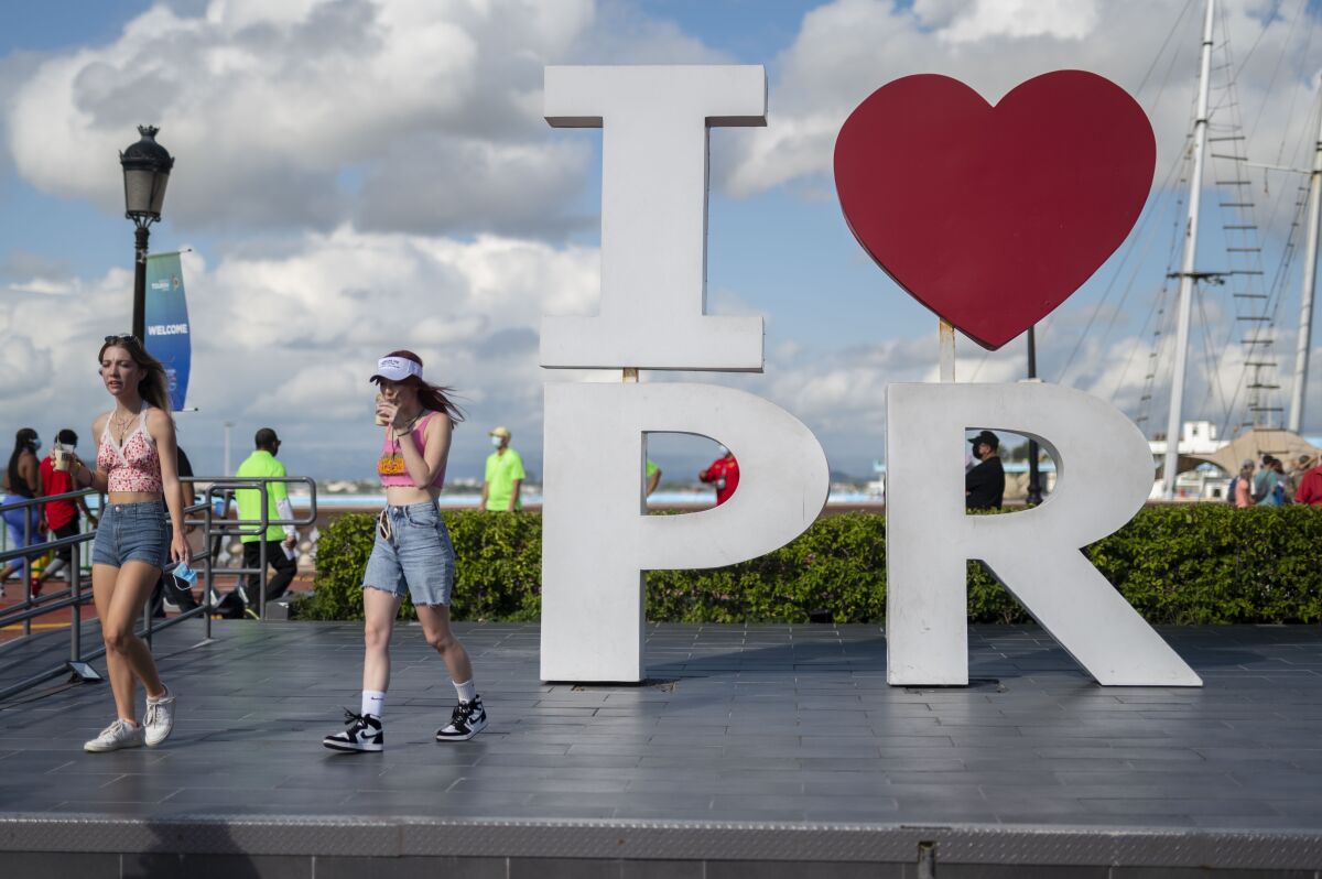 Tourists walk through the docking area after exiting Carnival's Mardi Gras cruise ship, docked in the bay of San Juan, Puerto Rico, Tuesday, Aug. 3, 2021, marking the first time a cruise ship visits the U.S. territory since the COVID-19 pandemic began. (AP Photo/Carlos Giusti)