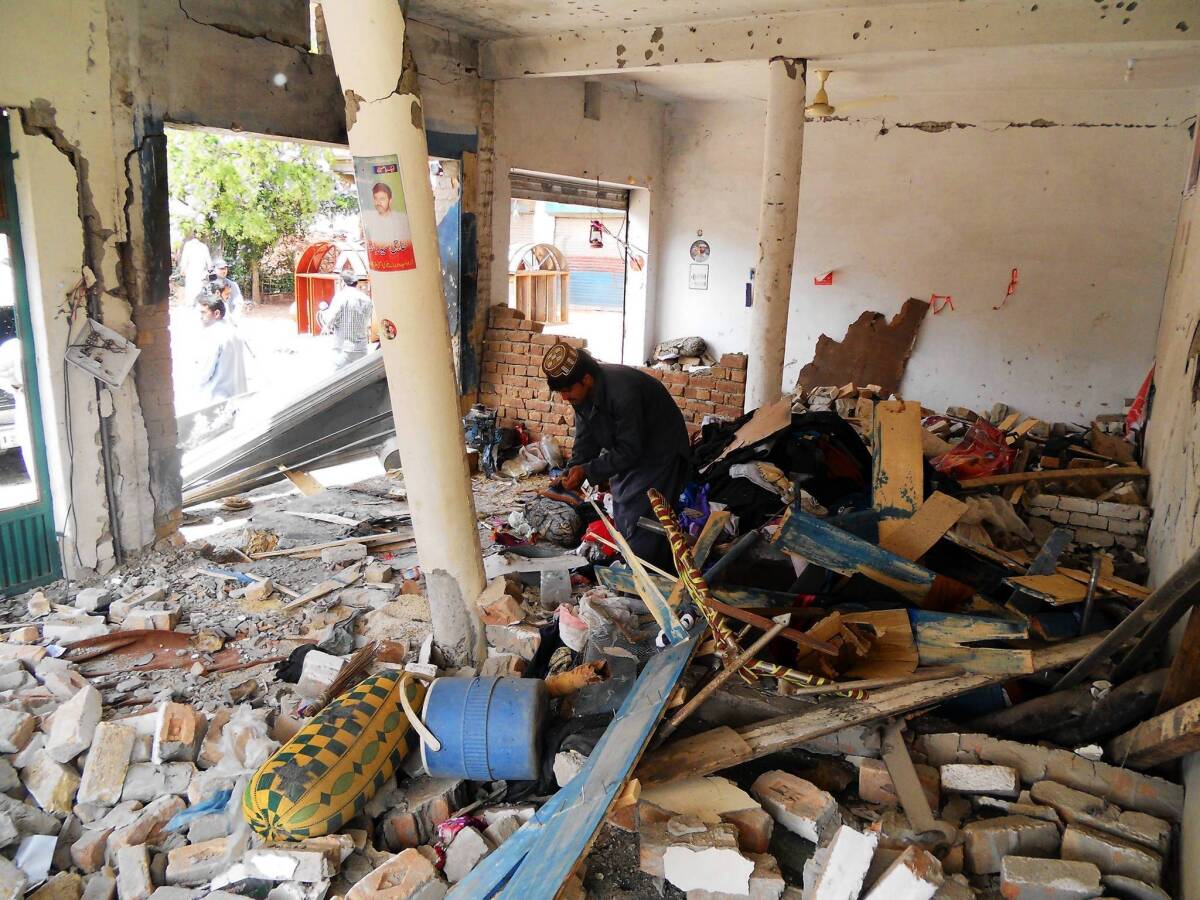 A Pakistani man looks at debris in the destroyed office of an election candidate after a bombing in the city of Kohat.