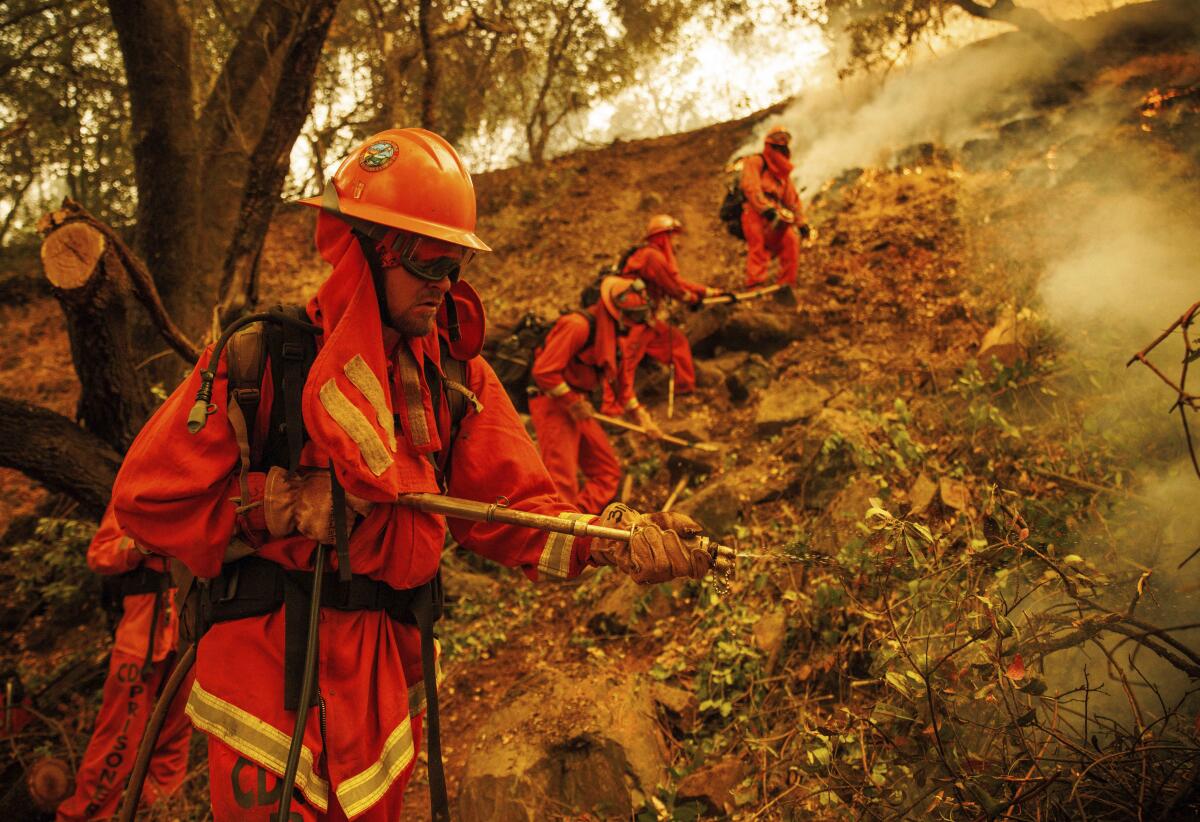 Inmate firefighters spray water as a fire burns