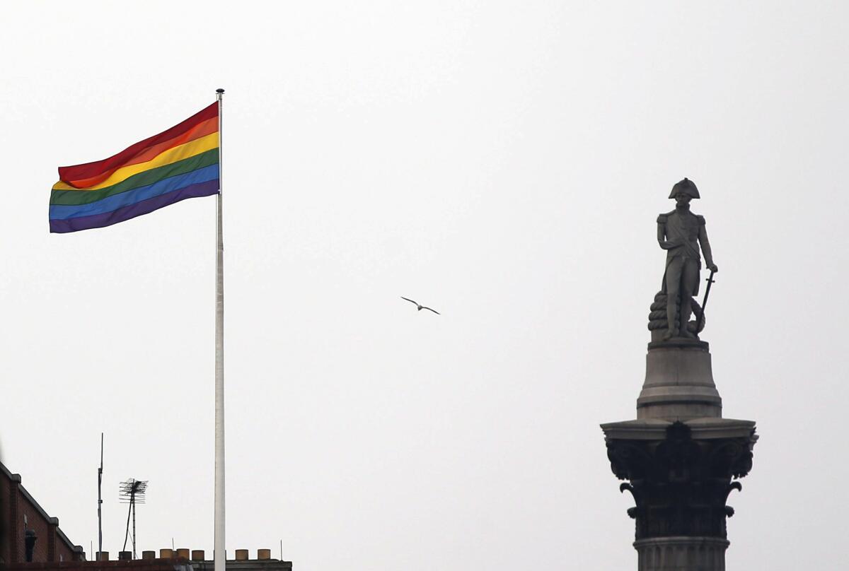 The rainbow flag flies over a building next to Nelson's Column monument.