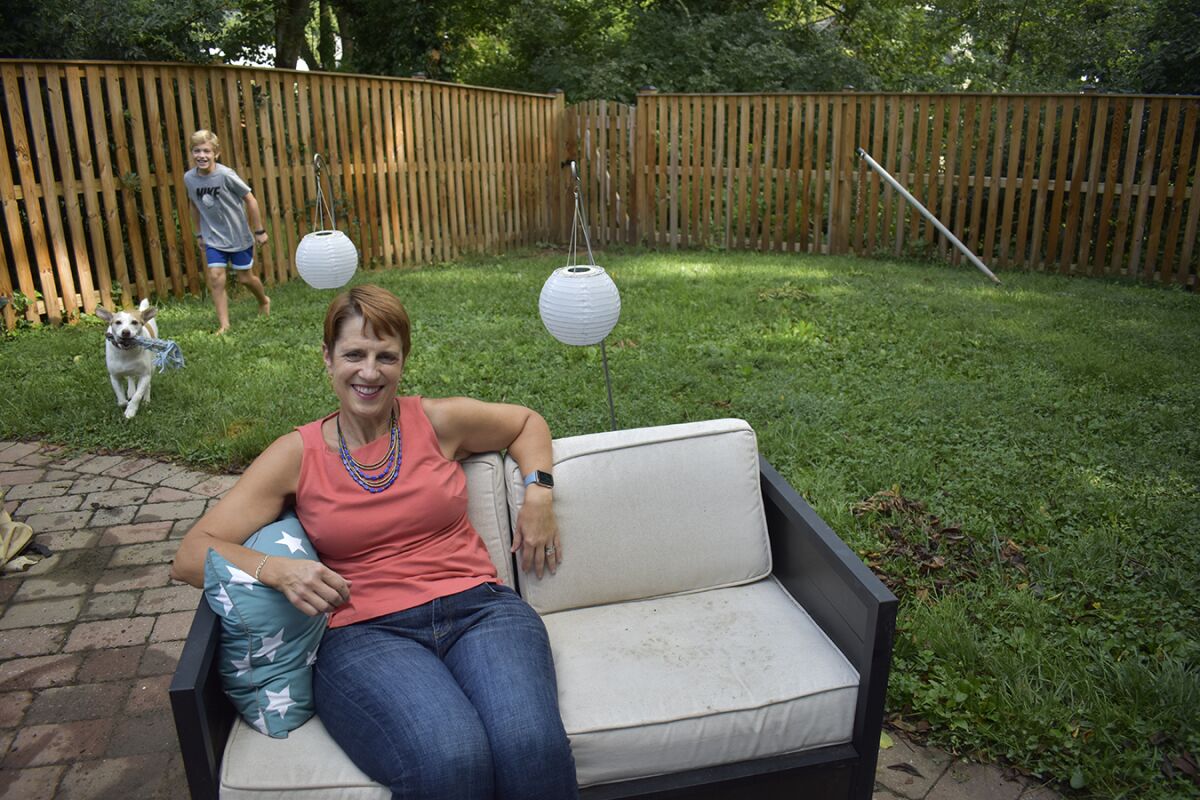 Angie Melton sits down in a backyard with a child and do playing in the background