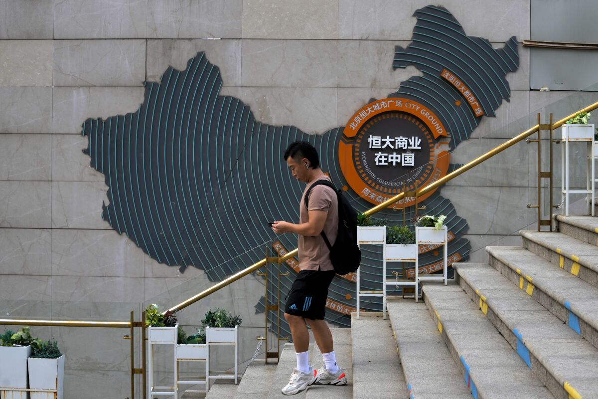 A man walks by a map showing Evergrande development projects in China, at an Evergrande city plaza in Beijing, Wednesday, Sept. 15, 2021. One of China's biggest real estate developers is struggling to avoid defaulting on billions of dollars of debt, prompting concern about the broader economic impact and protests by apartment buyers about delays in completing projects. Rating agencies say Evergrande Group appears likely to be unable to repay all of the 572 billion yuan ($89 billion) it owes banks and other bondholders. That might jolt financial markets, but analysts say Beijing is likely to step in to prevent wider damage. (AP Photo/Andy Wong)