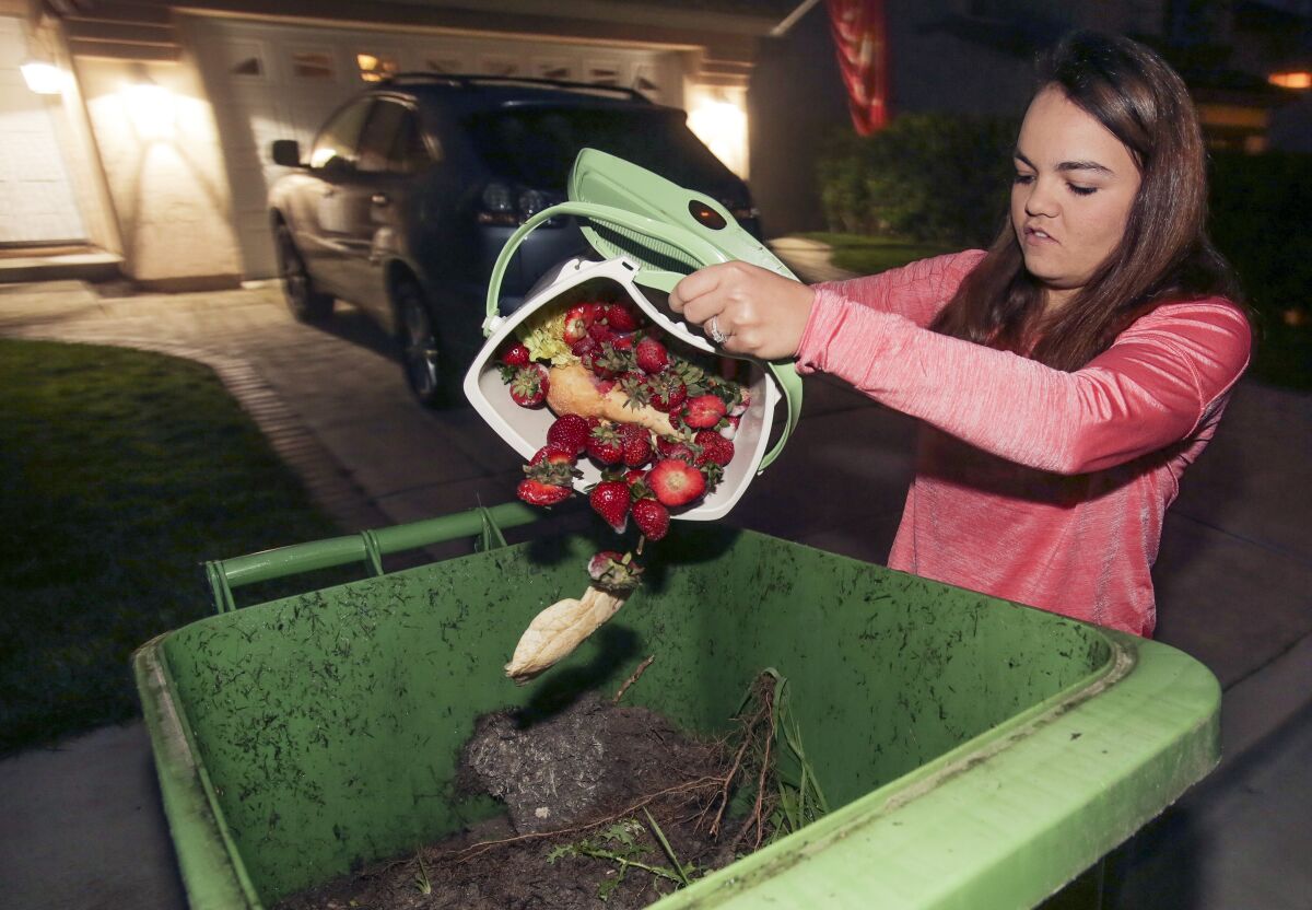 Oceanside resident Chelsee Brown deposited food scraps into a green trash bin in front of her house in 2017. 