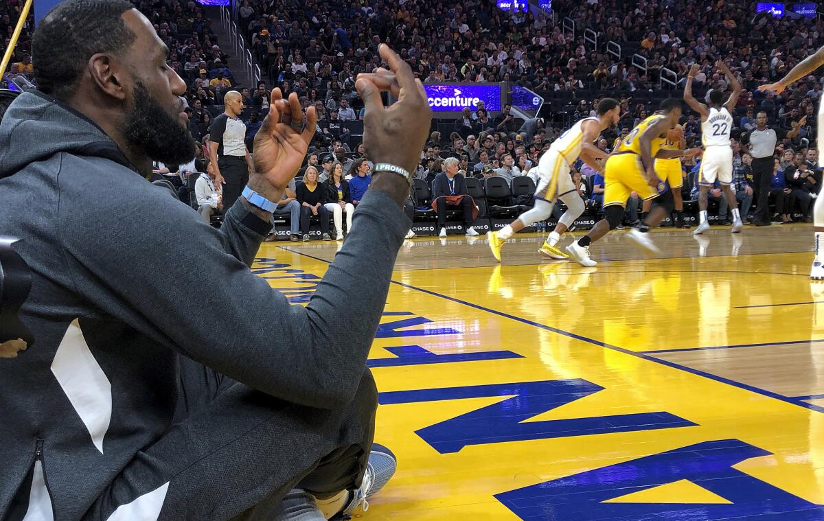 Lakers forward LeBron James sits along the baseline, appearing to meditate, during the exhibition game against the Warriors on Friday.