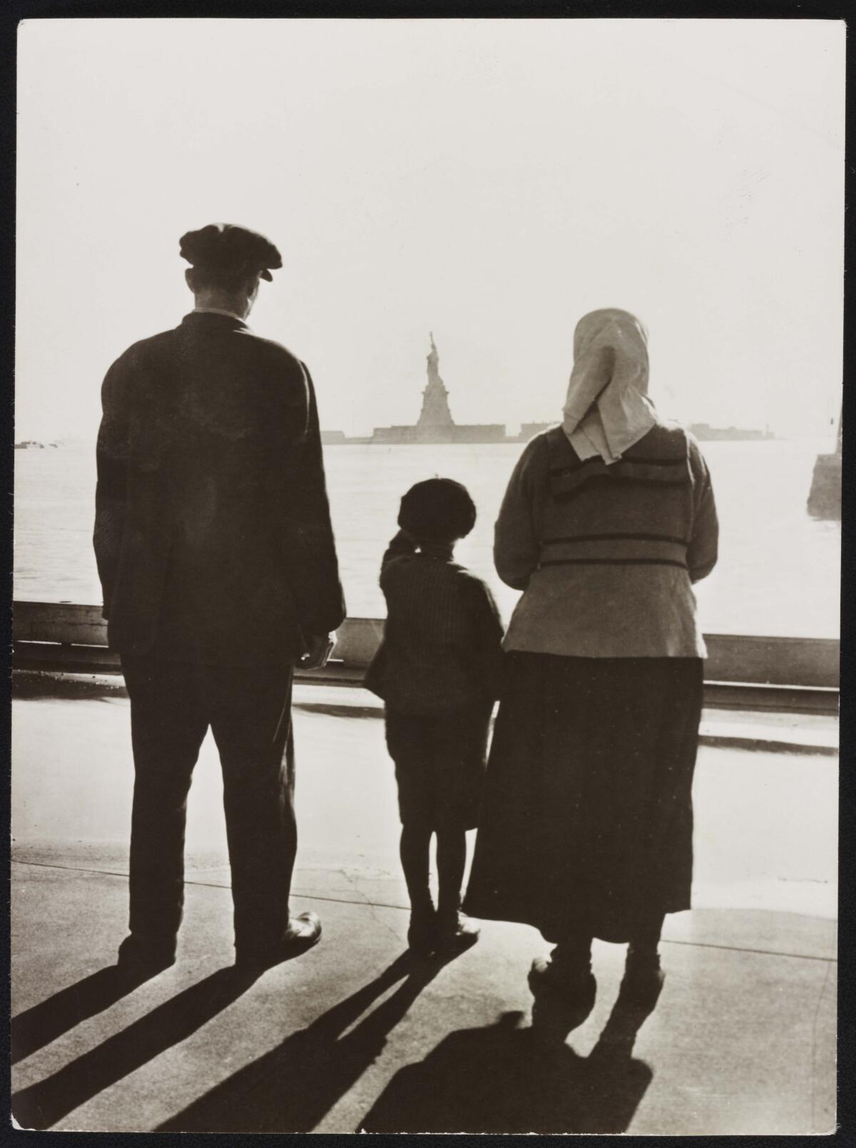 A photo from "The U.S. and the Holocaust" shows an immigrant family looking across the water to the Statue of Liberty.
