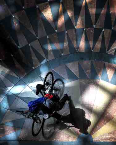 An overhead view of a person with a bike on an ornate tiled floor.