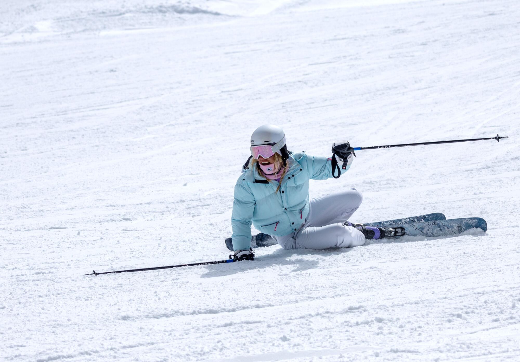 A helmeted skier grins after taking a fall. 