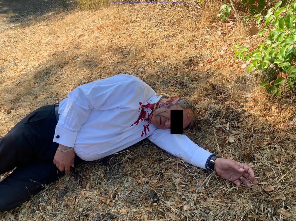 A court exhibit photo shows a man with fake blood on his shirt pretending to be dead.