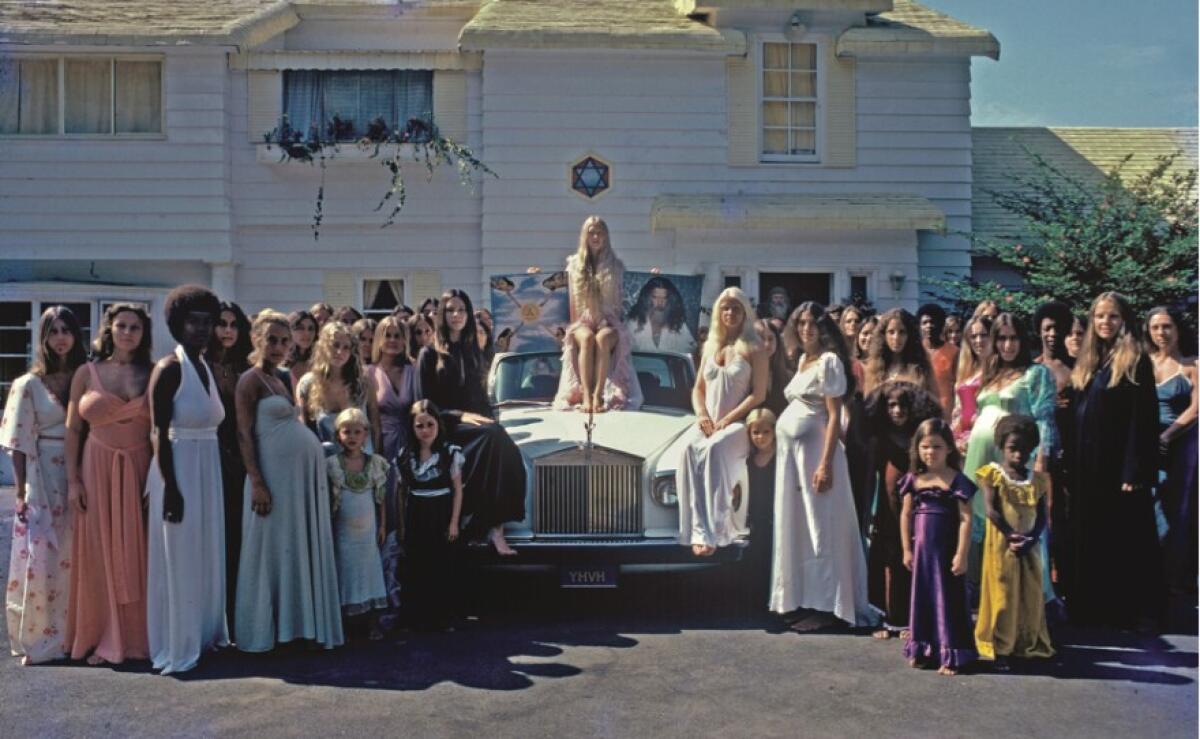 Women in long dresses pose surrounding a Rolls Royce in the 1970s
