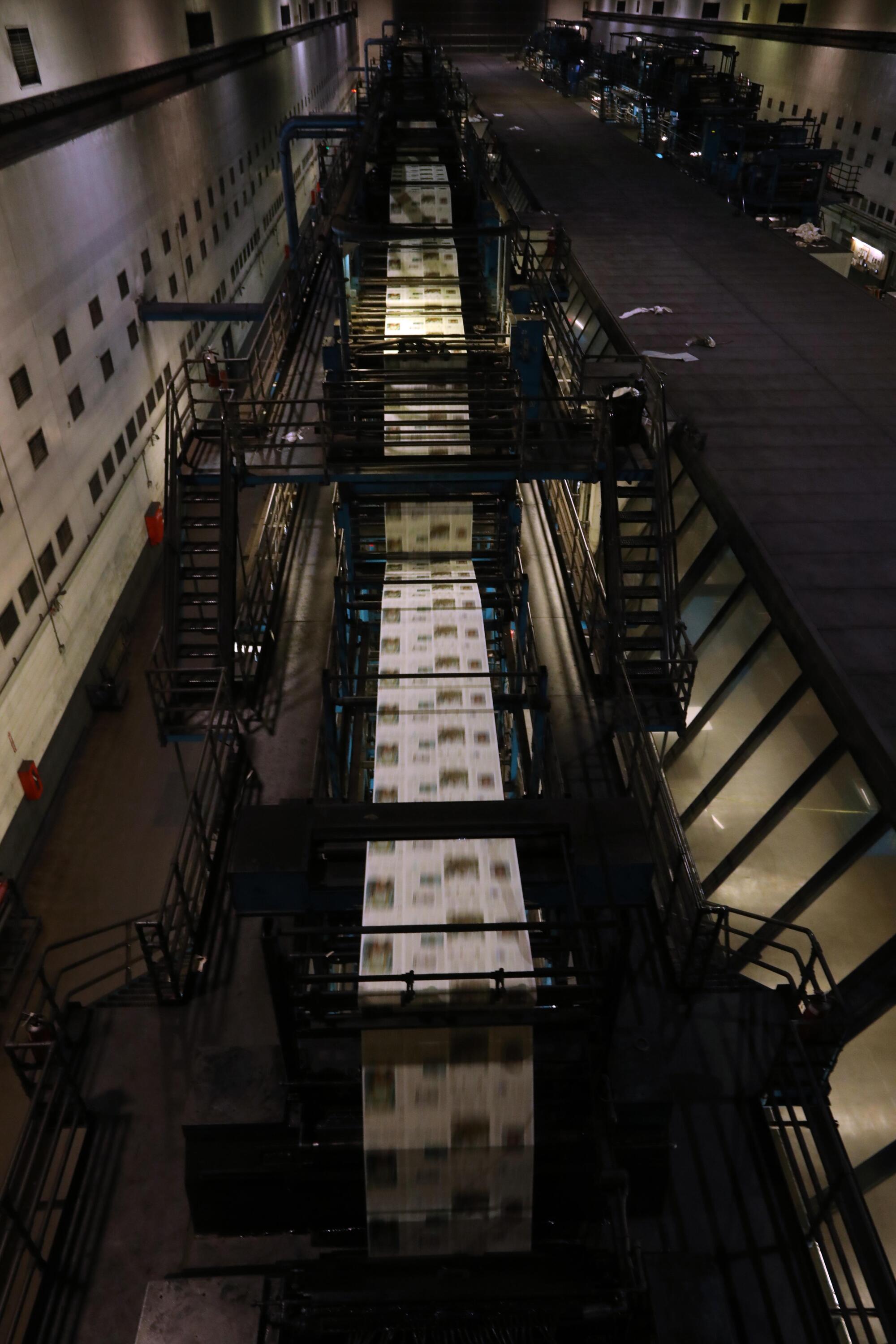 A view from the catwalk captures newspapers rolling off the presses