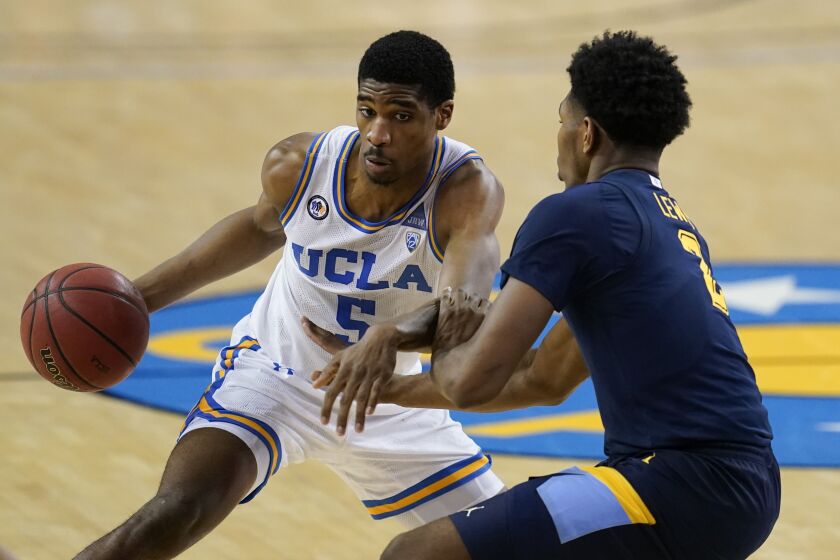 UCLA guard Chris Smith, left, is defended by Marquette forward Justin Lewis during the second half.