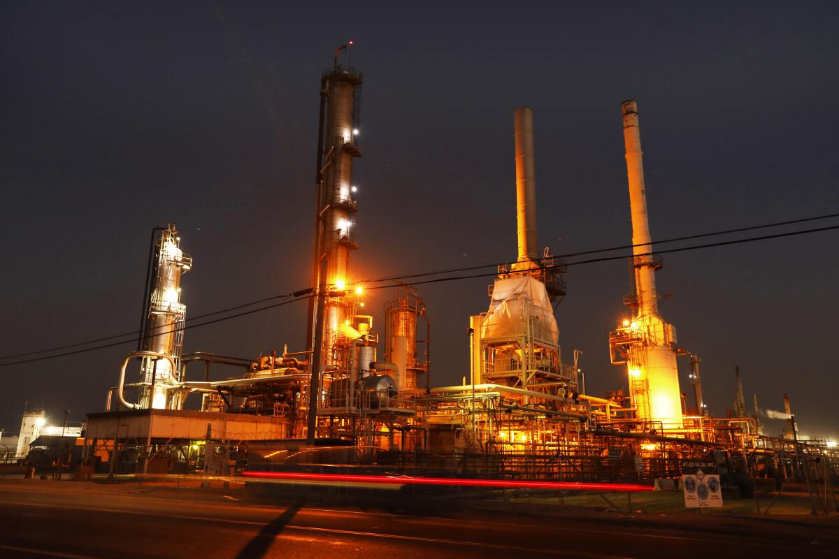 Towers lighted up at night at an oil refinery. 