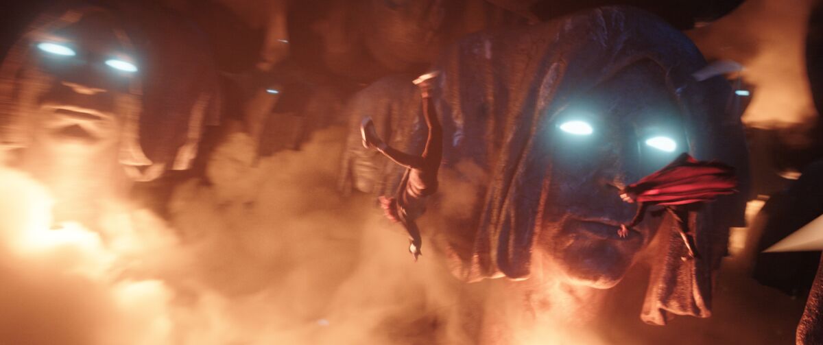Two people tumble through the multiverse with giant beings looking on in "Doctor Strange Multiverse of Madness."