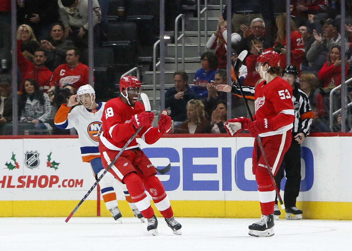 Detroit Red Wings right wing Givani Smith (48) celebrates his goal with defenseman Moritz Seider (53) as New York Islanders defenseman Andy Greene (4) skates nearby during the second period of an NHL hockey game Saturday, Dec. 4, 2021, in Detroit. (AP Photo/Duane Burleson)