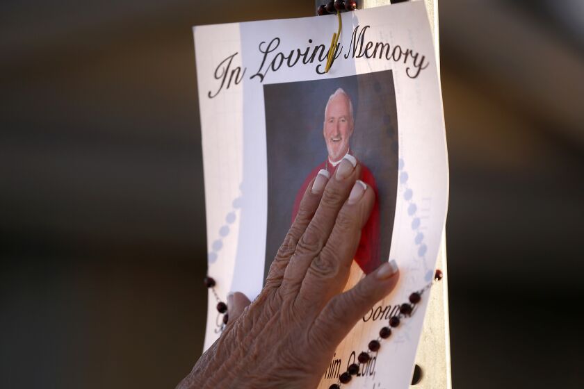 HACIENDA HEIGHTS, CALIF. - FEB. 19, 2023. A woman touches a picture of Roman Catolic Bishop David O'Connell, who died from a gunshot wound at his Hacienda Heights home on Saturday, Dec. 18, 2023. Police are investigating the case as a homicide. (Luis Sinco / Los Angeles Times)