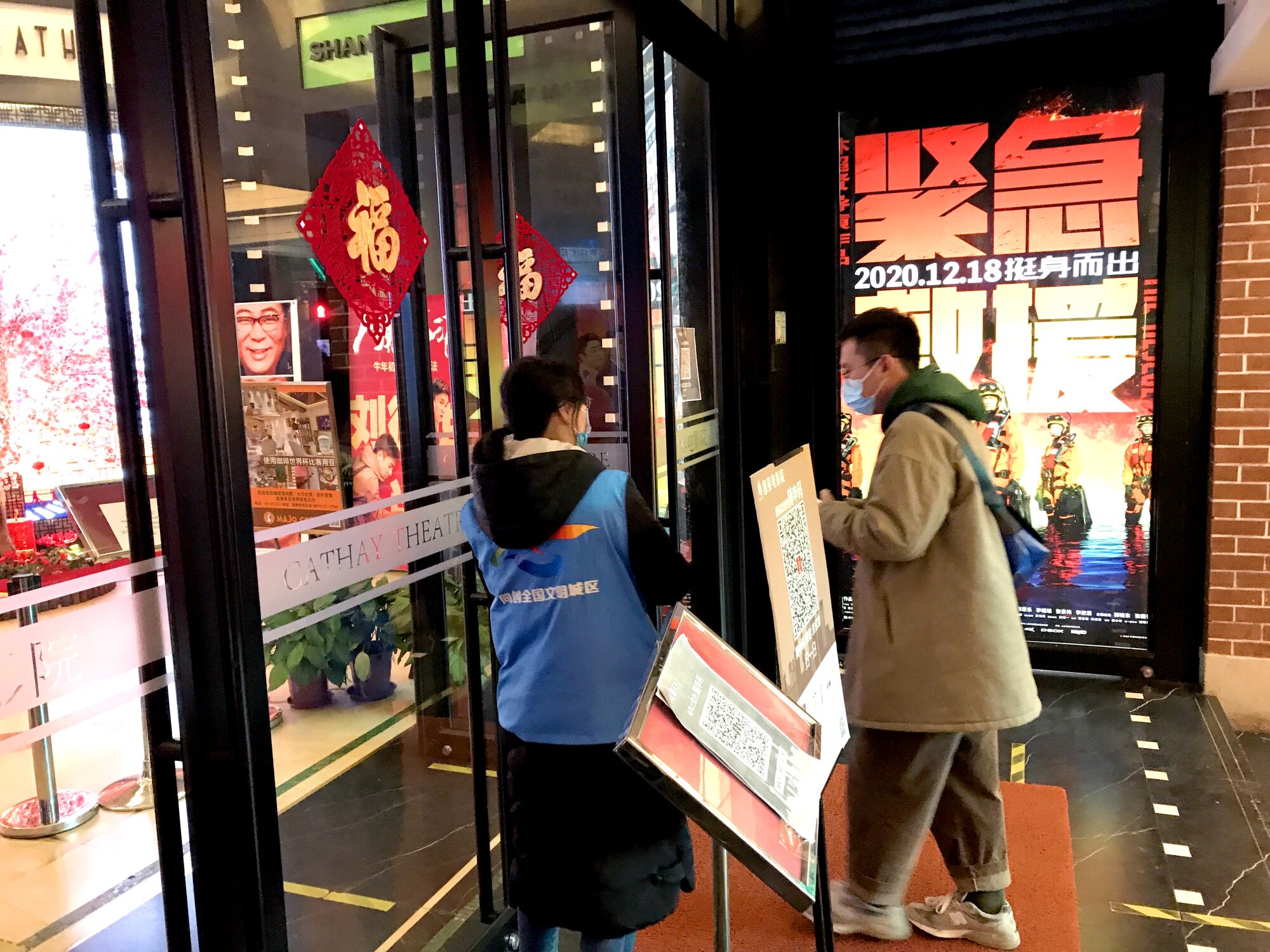 A cinema worker interacts with a moviegoer outside a theater in China.