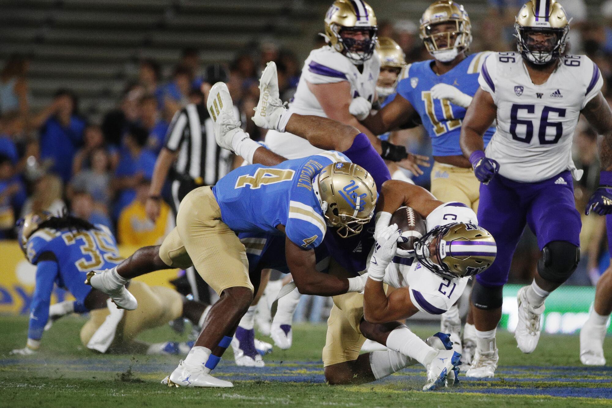 UCLA defensive back Stephan Blaylock tackles Washington Huskies running back Wayne Taulapapa.